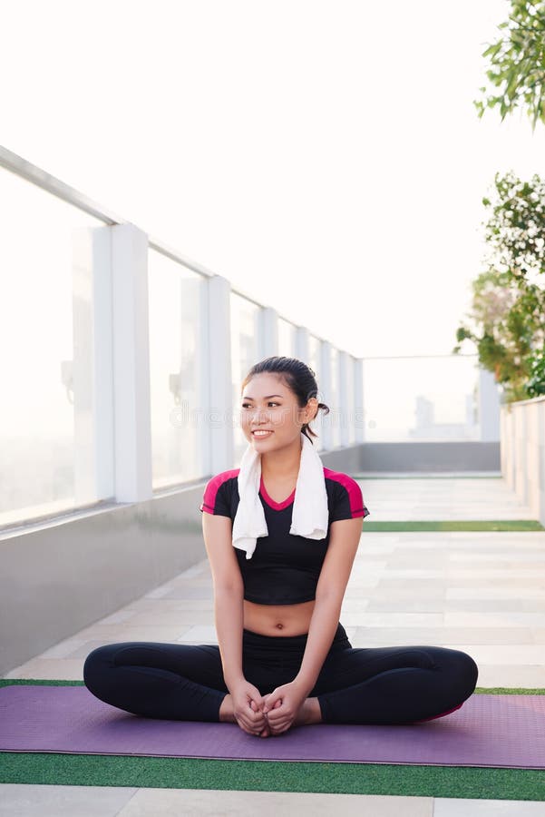 Young beautiful Asian woman sitting on yoga mat and smiling in morning. Sport and healthy lifestyle stock images Young beautiful Asian woman sitting on yoga mat and smiling in morning. Sport and healthy lifestyle stock images