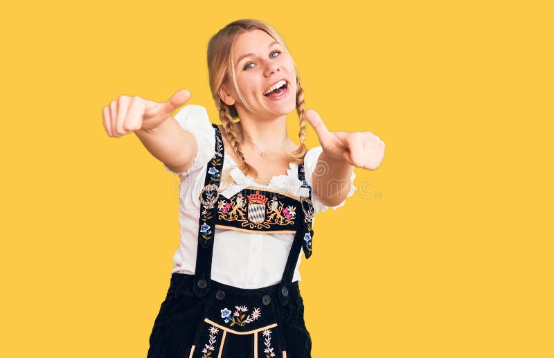 Young beautiful blonde woman wearing oktoberfest dress approving doing positive gesture with hand, thumbs up smiling and happy for