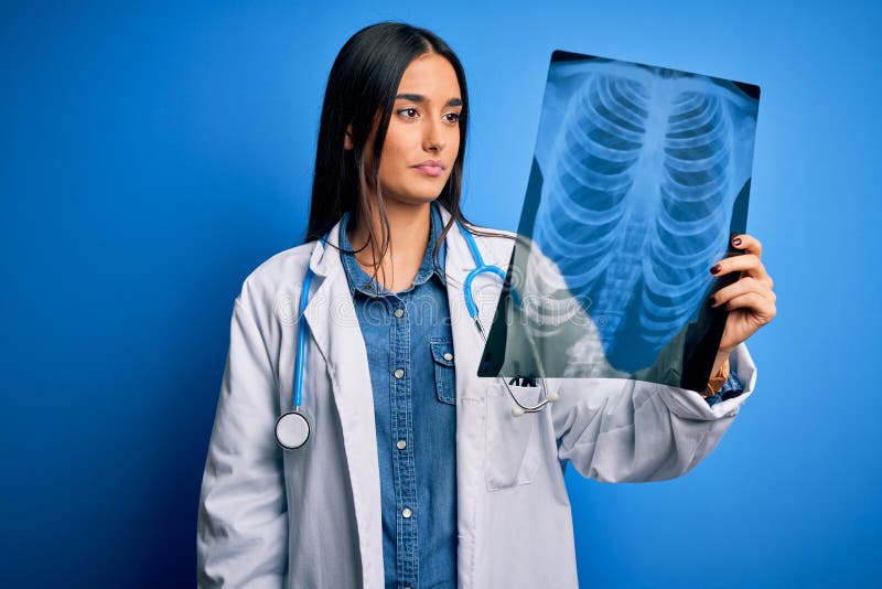 Young beautiful brunette doctor woman wearing stethoscope holding chest xray with a confident expression on smart face thinking