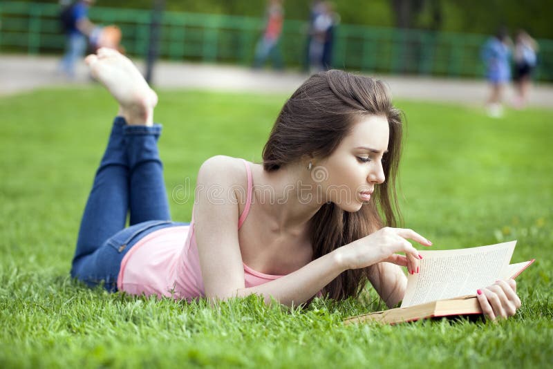 Young beautiful brunette girl reading a book outdoor