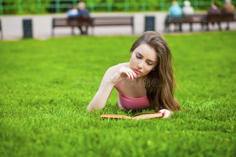 Young beautiful brunette girl reading a book outdoor