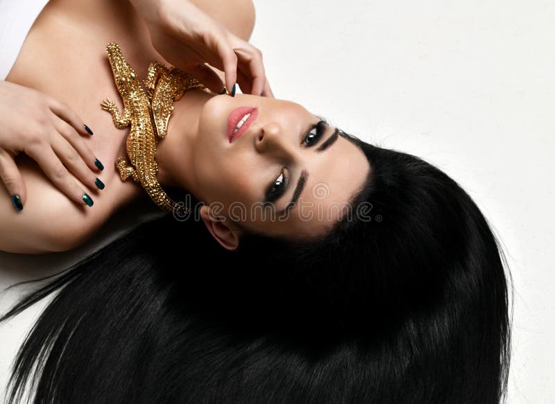 Young beautiful brunette woman lying on the floor wear expensive gold crocodile jewellery with long hair royalty free stock images Young beautiful brunette woman lying on the floor wear expensive gold crocodile jewellery with long hair royalty free stock images