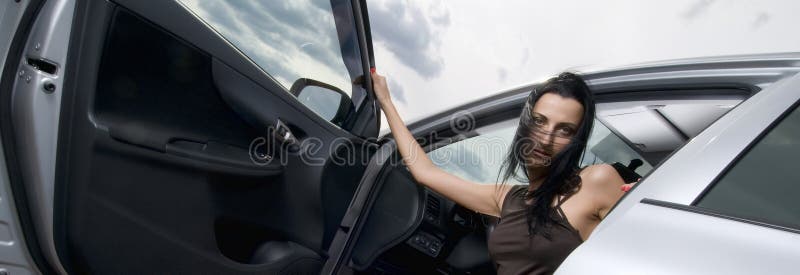 Young beautiful brunette woman open door of motor vehicle sitting inside the car