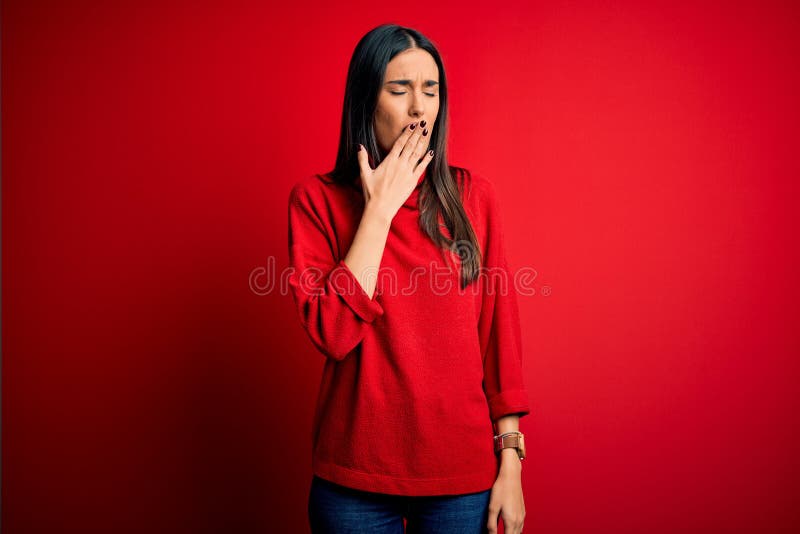 Young beautiful brunette woman wearing casual sweater over isolated red background bored yawning tired covering mouth with hand