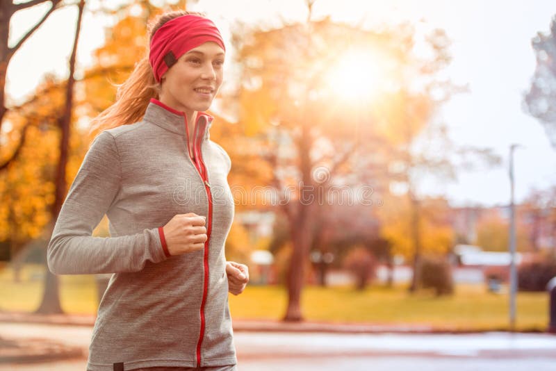 Young beautiful caucasian woman jogging workout training. Autumn running fitness girl in city urban park environment