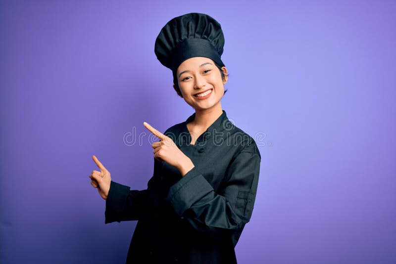 Young beautiful chinese chef woman wearing cooker uniform and hat over purple background smiling and looking at the camera