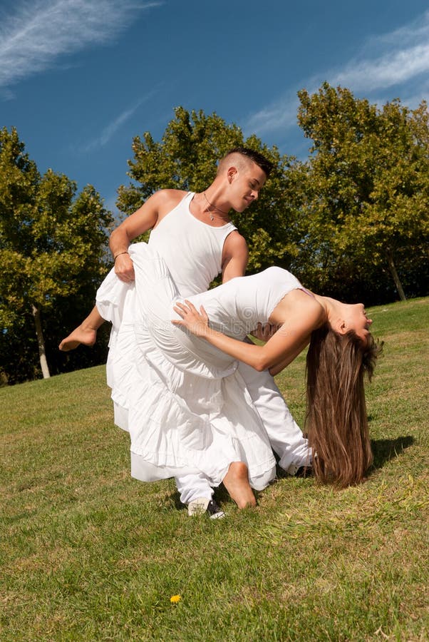 Young beautiful couple dance and embrace on grass