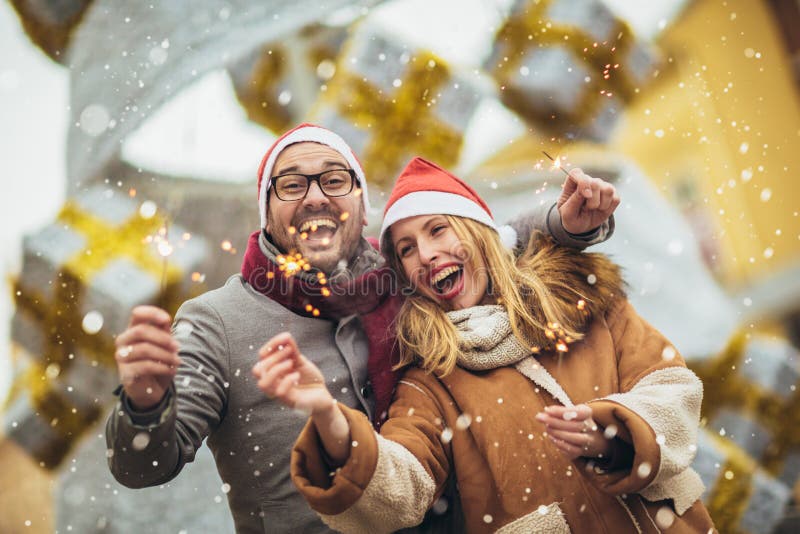 Beautiful couple with Santa hats holding sprinklers in the city royalty free stock photo Beautiful couple with Santa hats holding sprinklers in the city royalty free stock photo
