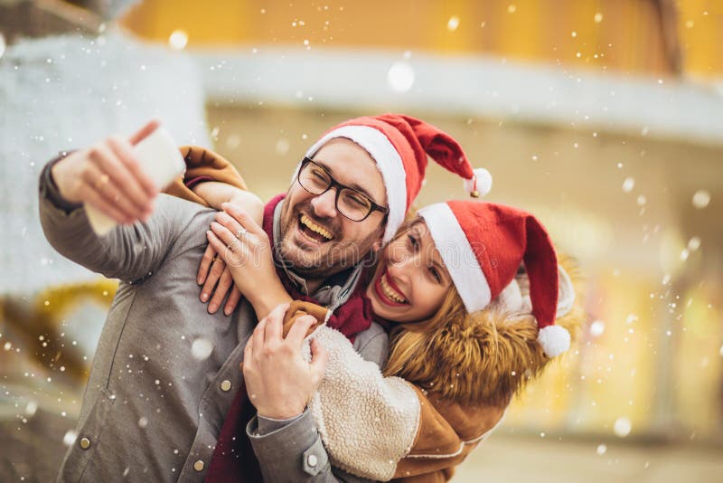 Beautiful couple with Santa hats make selfie photo in the city stock images Beautiful couple with Santa hats make selfie photo in the city stock images