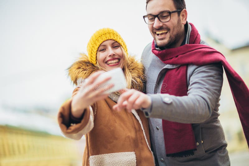 Beautiful couple with Santa hats make selfie photo in the city stock photos Beautiful couple with Santa hats make selfie photo in the city stock photos