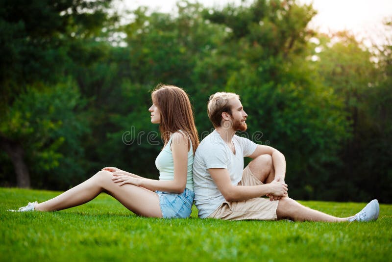 Sitting and smiling. Beautiful young smiling couple in Park.