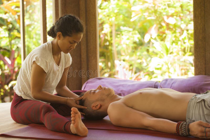 Young beautiful and exotic Asian Thai therapist woman giving traditional he...