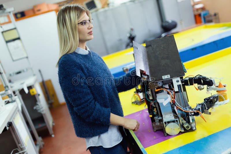 Young Beautiful Female Engineer Testing Robot in Stock Image