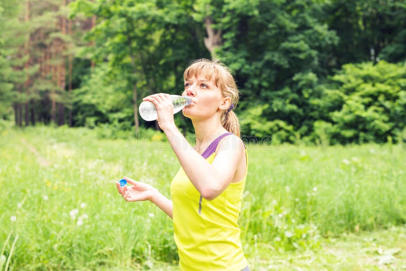 Young beautiful fit woman drink water after her exercise.