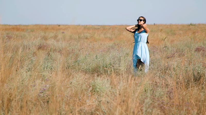 Young Beautiful Girl in a Blue Dress Enjoys Flowers Steppe. a Young Woman in a Meadow. Steppe. Blossoming Sunny Meadow Stock Footage - Video of beauty, model: 77302656->