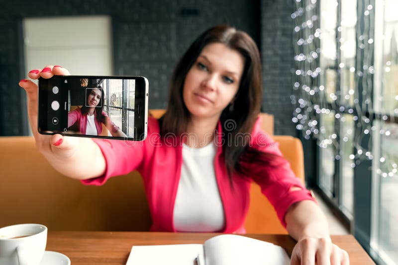Young beautiful girl doing selfie sitting in cafe stock image