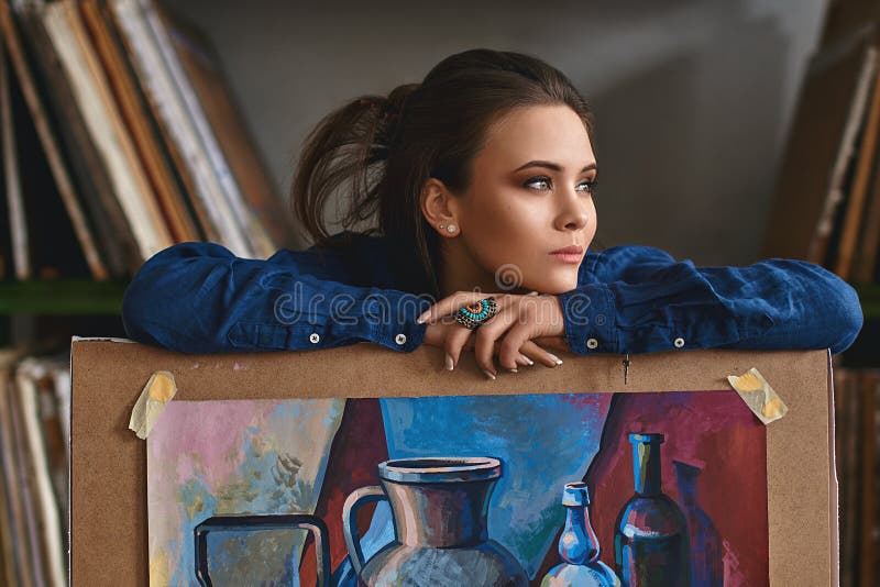 Young beautiful girl, female artist painter thinking of a new artwork idea or project holding a finished picture artwork stock photos Young beautiful girl, female artist painter thinking of a new artwork idea or project holding a finished picture artwork stock photos