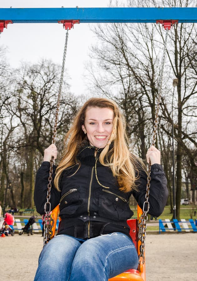 Young beautiful girl having fun riding a chain-swing in the park