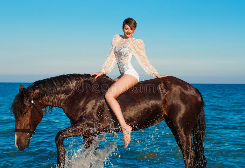 Young beautiful girl with a horse on the beach