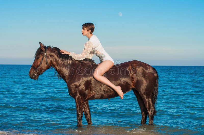 Young beautiful girl with a horse on the beach