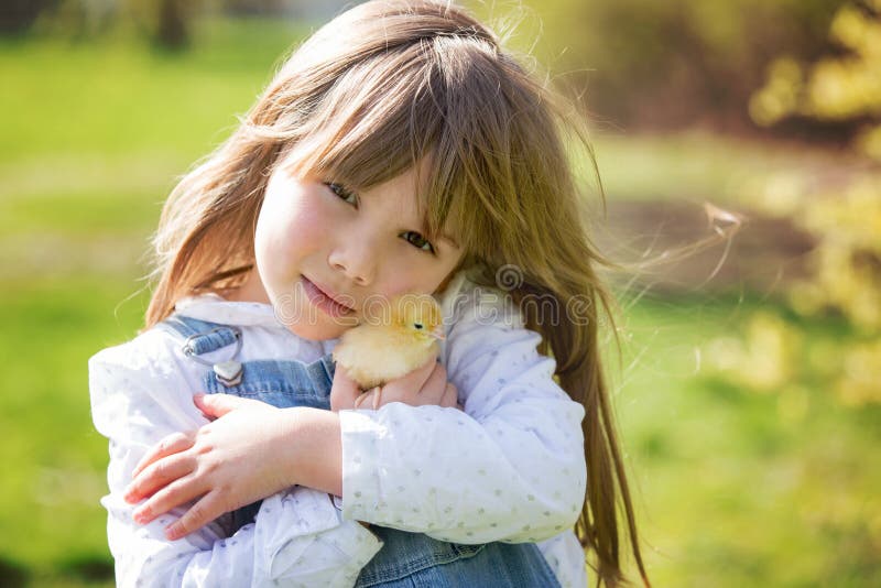 Young beautiful girl, playing with little newborn chick in the p