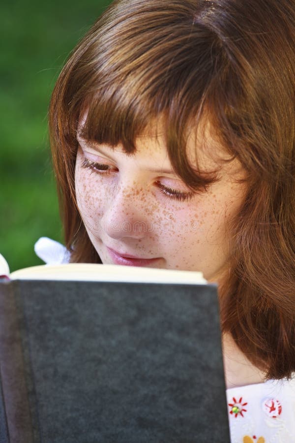 Young beautiful girl reading a book outdoor