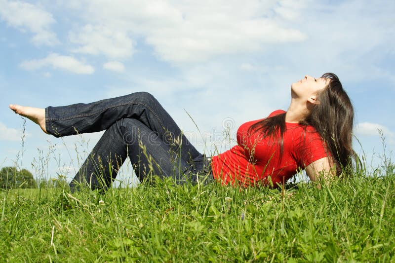 Young beautiful girl in red shirt lies on grass