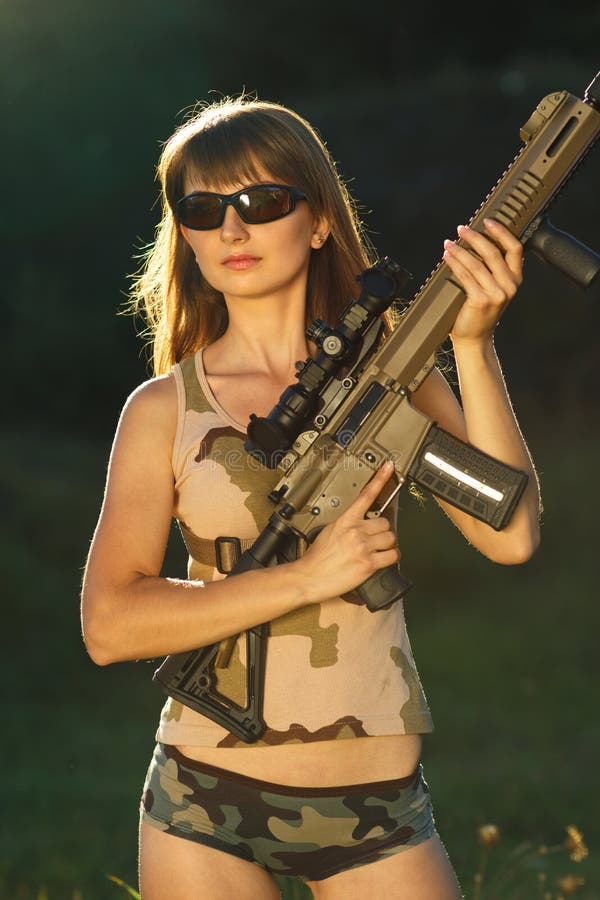 Young beautiful girl in camouflage with a shotgun in an outdoor. Young beautiful girl in camouflage with a shotgun in an outdoor