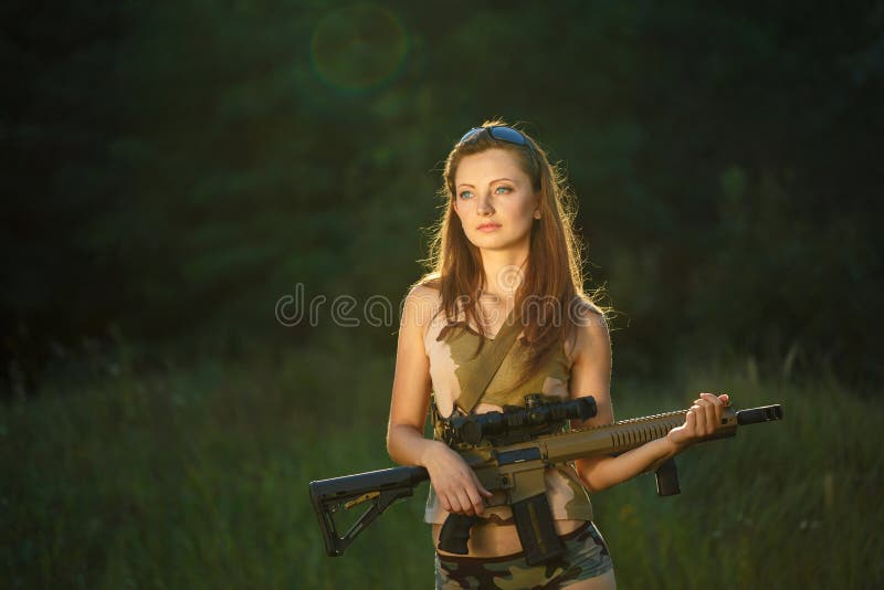 Young beautiful girl in camouflage with a shotgun in an outdoor. Young beautiful girl in camouflage with a shotgun in an outdoor