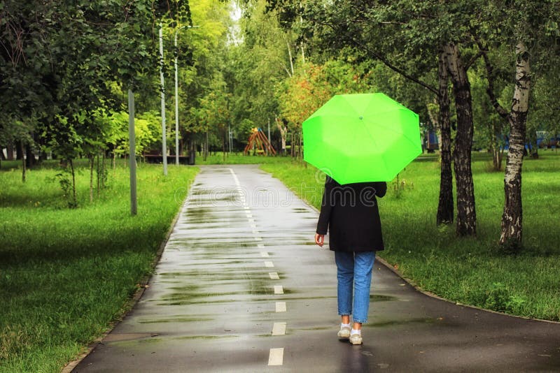 Young Beautiful Girl Walking Alone Under Green Umbrella In The City Park In Summertime Stock