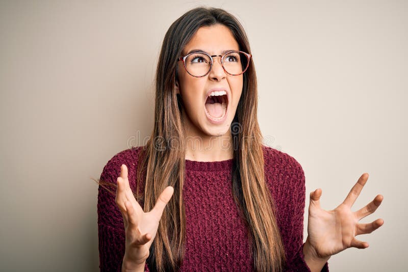 Young beautiful girl wearing casual sweater and glasses over isolated white background crazy and mad shouting and yelling with