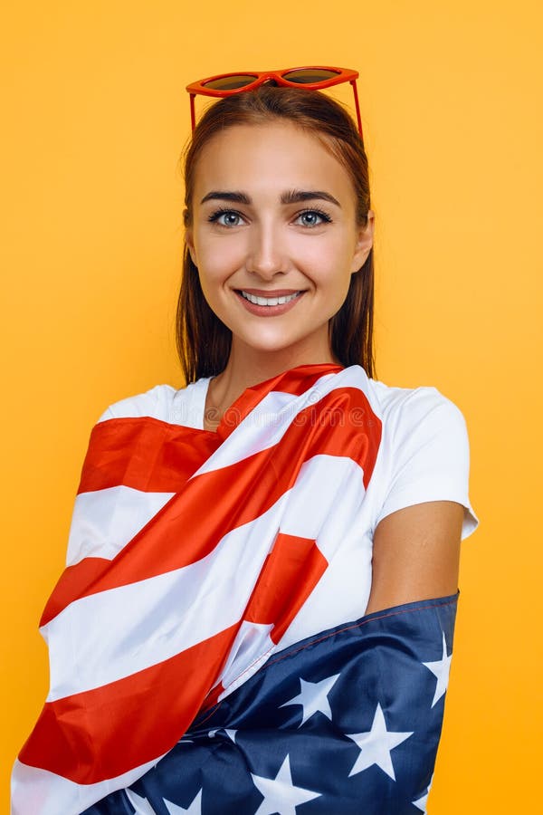 Young beautiful girl in a white t-shirt with the American flag, on a yellow background royalty free stock image Young beautiful girl in a white t-shirt with the American flag, on a yellow background royalty free stock image