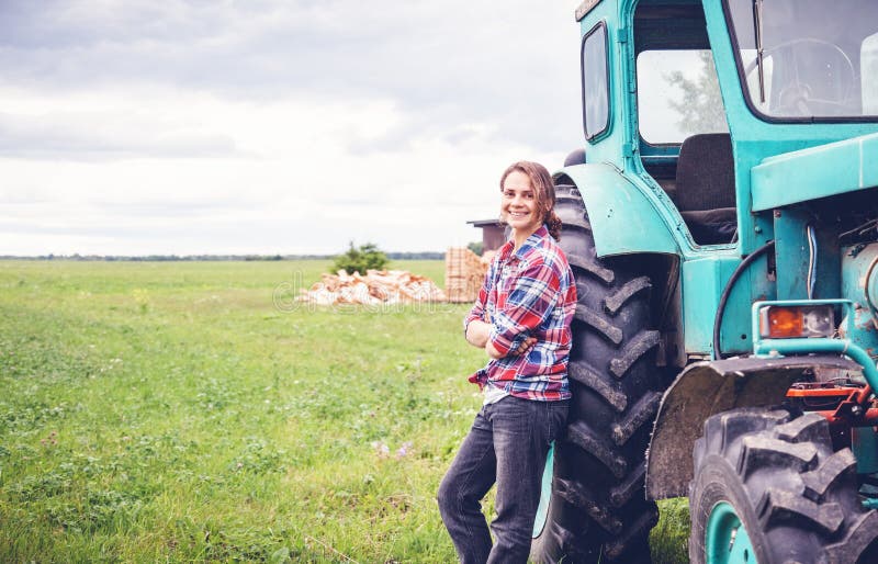 Young beautiful girl working on a tractor in the field, unusual work for women, a gender equality concept