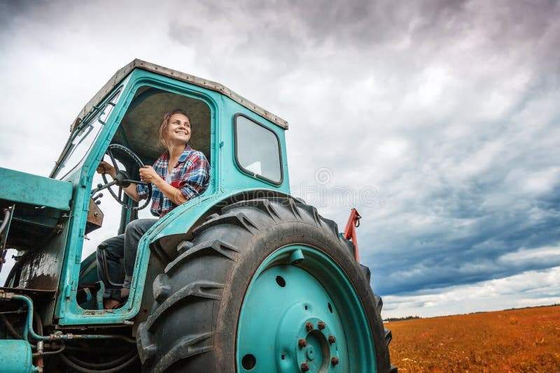 Young beautiful girl working on a tractor in the field, unusual