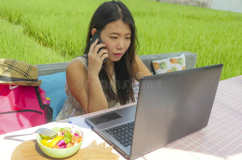 Young beautiful and happy Asian Chinese woman working outdoors with laptop computer networking green grass background cafe as digi