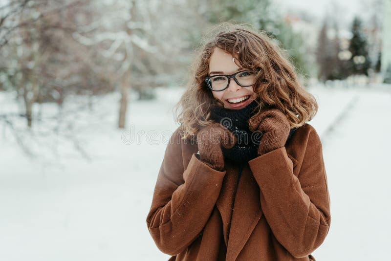 Young beautiful hipster woman in knitted scarf standing in the park and smiling. Winter fashion