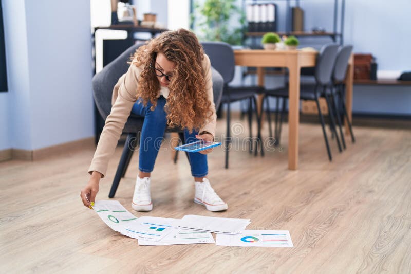 Young beautiful hispanic woman business worker using touchpad looking documents on floor at office royalty free stock photos