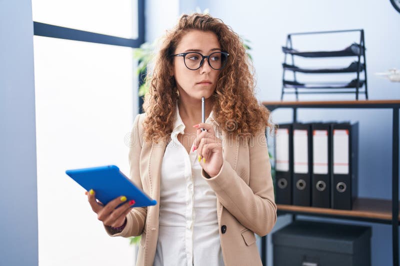 Young beautiful hispanic woman business worker using touchpad with serious expression at office royalty free stock image