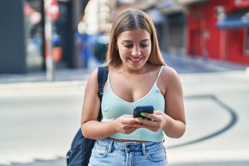 Young beautiful hispanic woman student smiling confident using smartphone at street stock images