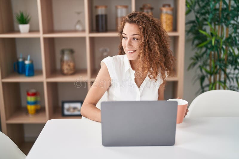 Young beautiful hispanic woman using laptop drinking coffee at home royalty free stock photo