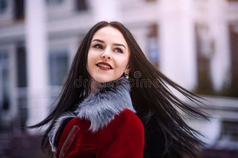 Young beautiful model in the city. Dynamically young girl walks down the street.Hair fluttering in the wind.