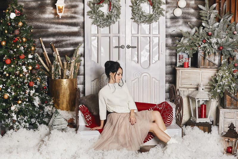 Young beautiful model girl in trendy skirt posing near Christmas tree in the rustic decorated interior. Fashion portrait