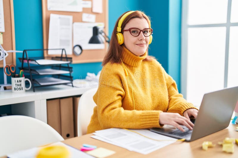 Young beautiful plus size woman business worker using laptop and headphones working at office