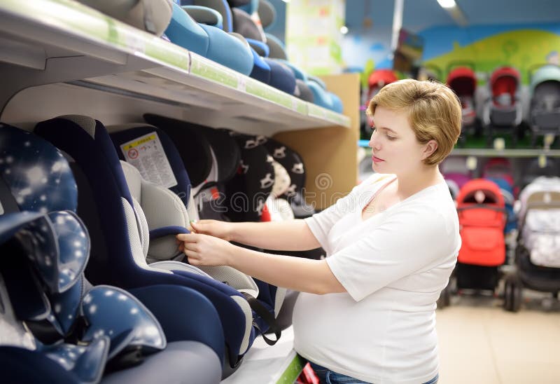 Young beautiful pregnant woman choosing infant car seat. Shopping for expectant mothers and baby royalty free stock photos Young beautiful pregnant woman choosing infant car seat. Shopping for expectant mothers and baby royalty free stock photos