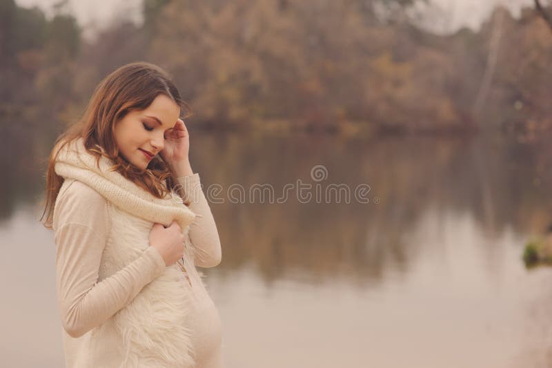 Giovani sognante bella donna incinta su accogliente, a piedi in autunno riverside, toni caldi, soft focus.