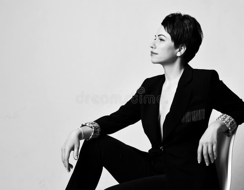 Young Beautiful Short Haired Brunette Woman In Elegant Business Suit With Deep Neckline Sitting