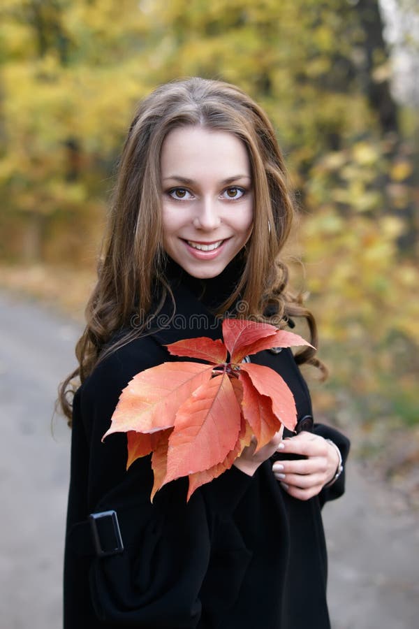 Young beautiful smiling girl with leaves.