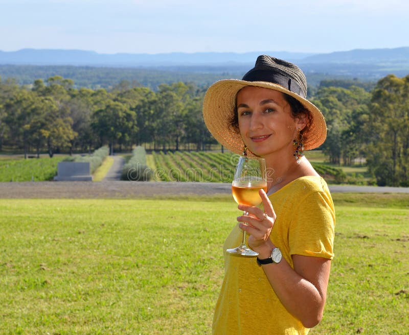 A young beautiful smiling woman wearing a hat and holding a glass cold white wine stock image