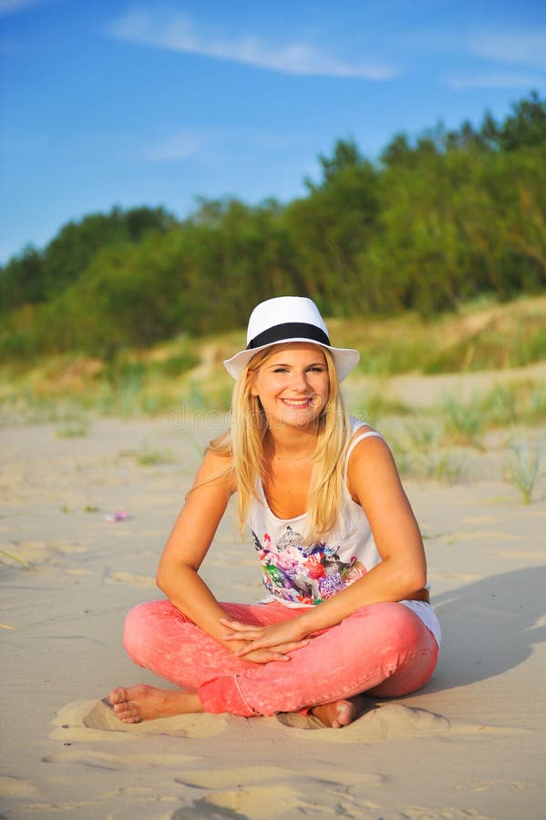 Young beautiful summer woman sitting on the beach