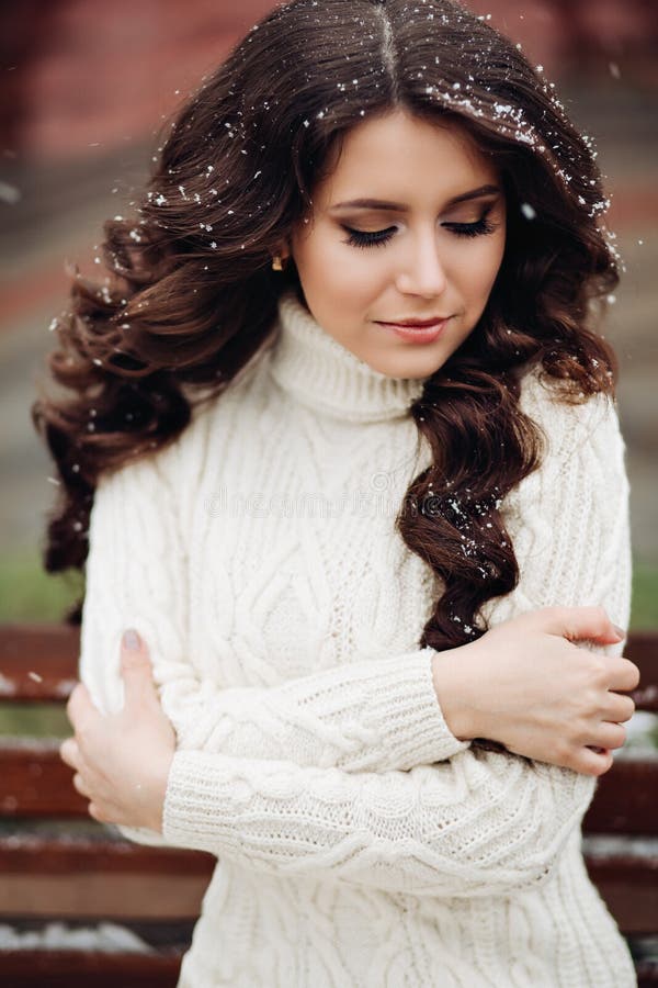 Young beautiful and very stylish girl with long dark hair poses in a long knitted white dress. Fashion portrait of stock images Young beautiful and very stylish girl with long dark hair poses in a long knitted white dress. Fashion portrait of stock images